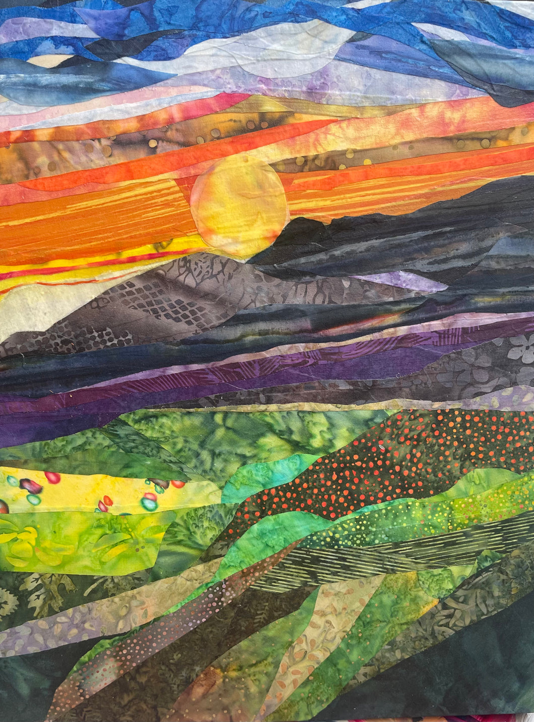 Abstract textile landscape artwork with layered sunset, rolling hills, and colorful fabric collage