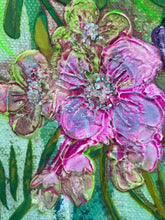 Close-up of pink flowers with crystal centers with green leaves on a textured surface