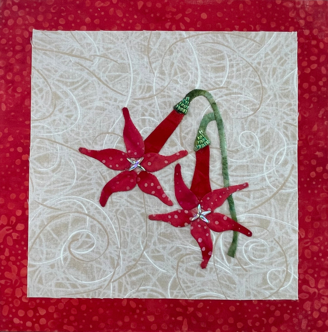 Two red fabric collage flowers with crystal centers and green stems on a neutral textile background, mounted on an 8x8 panel