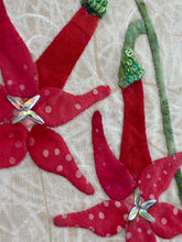 Close-up of red floral fabric applique with green leaves on beige fabric background