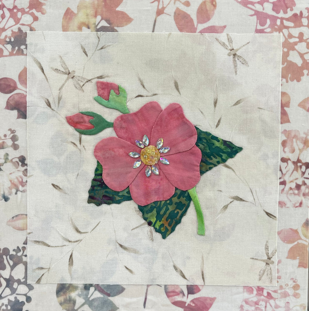 Coral pink fabric collage flower with crystal center on neutral textile background, mixed media botanical artwork on birch panel