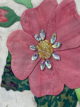 Close-up of pink fabric flower with a crystal decorative center on a textured background
