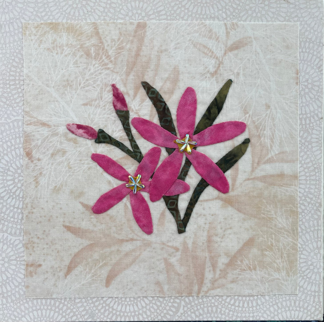 8 x 8 fabric collage artwork featuring pink flowers with crystal centers made from inherited textiles on neutral background