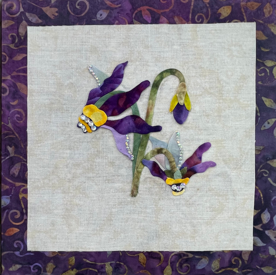 8 x 8 fabric collage artwork featuring purple and lavender flowers with curved stems and crystal embellishments made from inherited textiles
