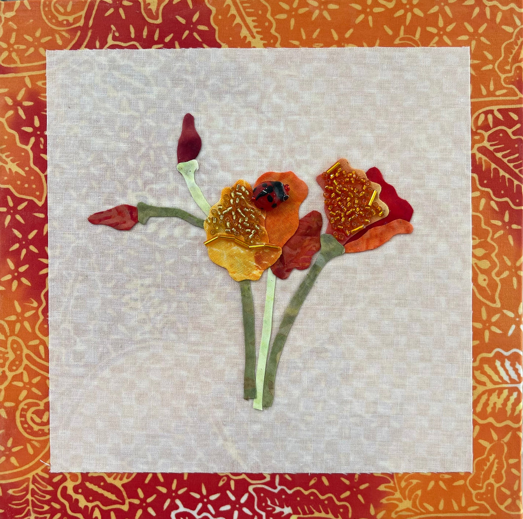 8 x 8 fabric collage artwork featuring orange and red flowers with bead embellishments and a small ladybug detail made from inherited textiles