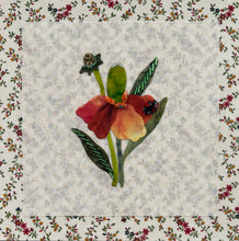 Floral quilt block with a red flower and green leaves on a textured fabric background.
