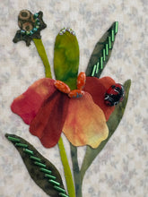 Close-up fabric art of a flower with a ladybug  and beads on a textured beige background