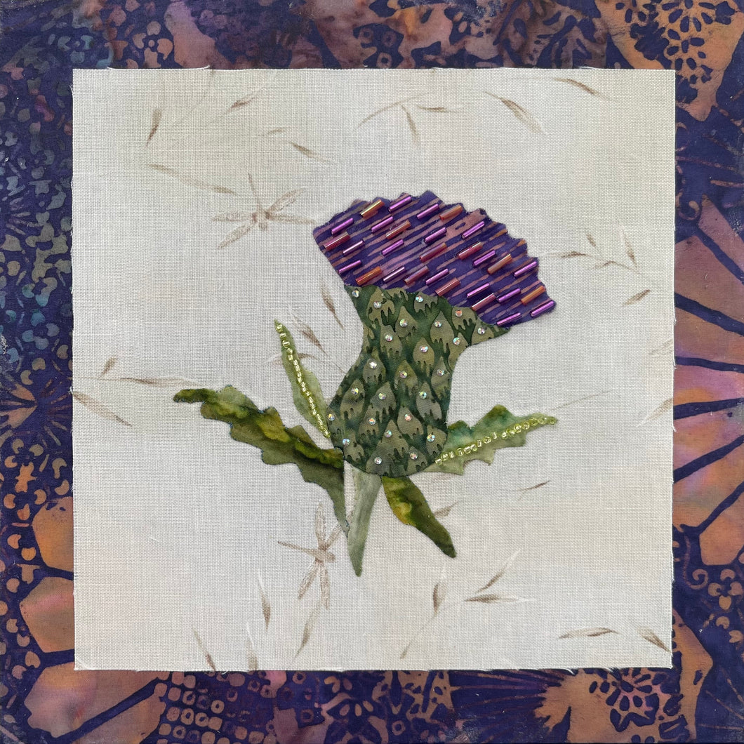 8 x 8 fabric collage artwork featuring a purple thistle flower with bead embellishments made from inherited textiles on neutral background