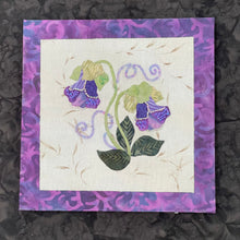 Hand-appliquéd purple bell-shaped floral textile artwork with detailed beadwork and layered fabric on a neutral background mounted on an 8x8 panel