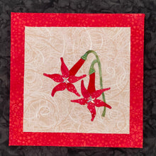 Fabric layered red flowers with crystals and beads on a beige background, framed by a red border.