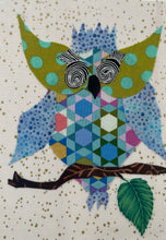 Whimsical fabric collage owl with patterned body, large spiral glasses, and blue dot wings perched on a branch with a leaf on a softly speckled background