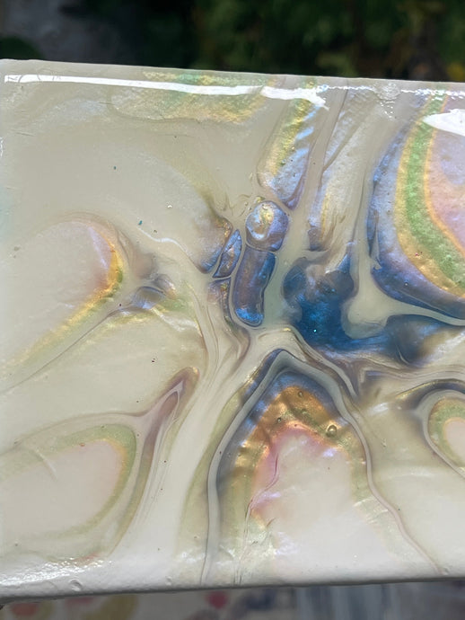 Quiet Tide resin artwork featuring luminous pearl, gold, blue, and soft green color-shifting pigments flowing across a glossy abstract surface in a floating frame.