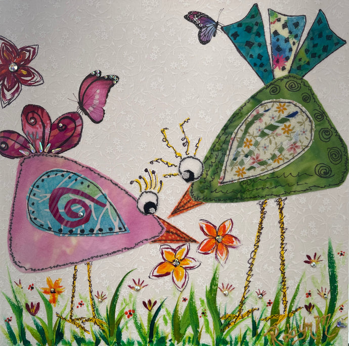Whimsical textile bird art showing two colorful birds facing each other with flowers and butterflies in a playful garden scene
