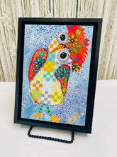 Colorful whimsical fabric collage bird with patchwork body, floral wings, and large expressive eyes on a blue textured background