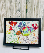 Whimsical fabric collage bird holding heart-shaped balloons on a colorful dotted background with playful stitched looking details 