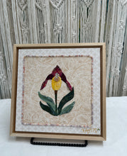 8 x 8 fabric collage artwork featuring a single yellow and burgundy flower made from inherited textiles with bead embellishments on neutral background