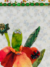 Close-up fabric art of a flower with a ladybug  and beads on a textured beige background