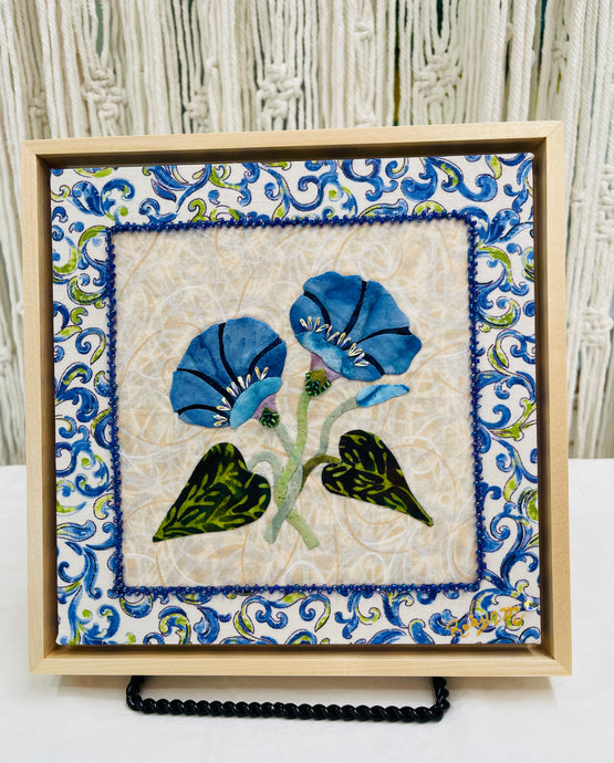 Artistic depiction of blue flowers and Swarovski crystals with green leaves on a textured beige background, surrounded by decorative blue floral patterns.