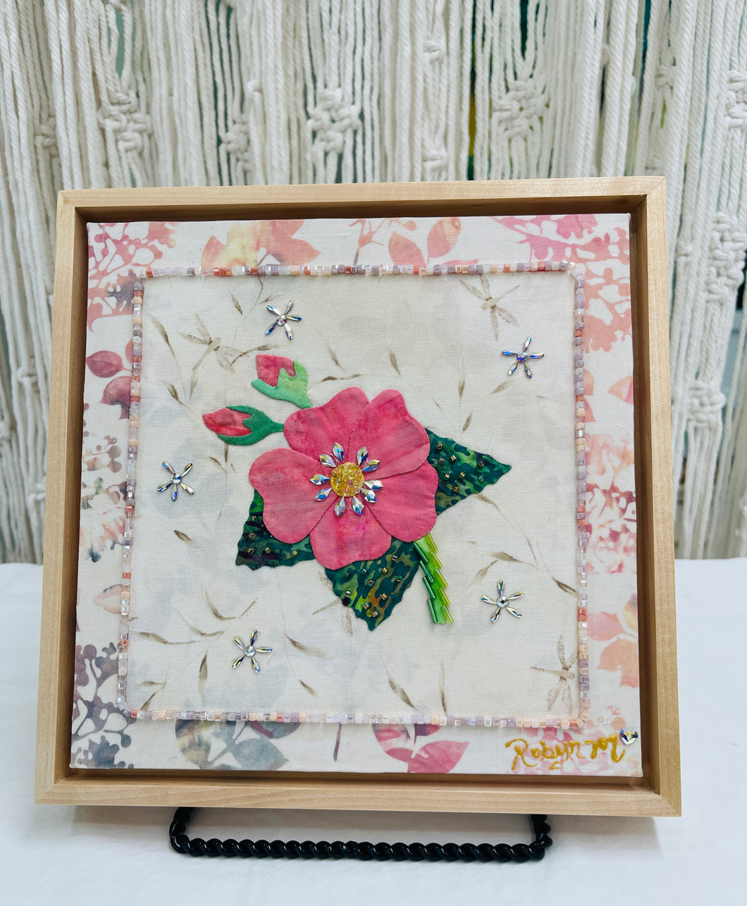 Coral pink fabric collage flower with Swarovski crystal center on neutral textile background, mixed media botanical artwork on birch panel