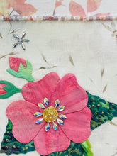 Close-up of pink fabric flower with a Swarovski crystal decorative center on a textured background