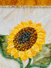 Close-up of a sunflower-shaped fabric piece with beaded center on a textured background