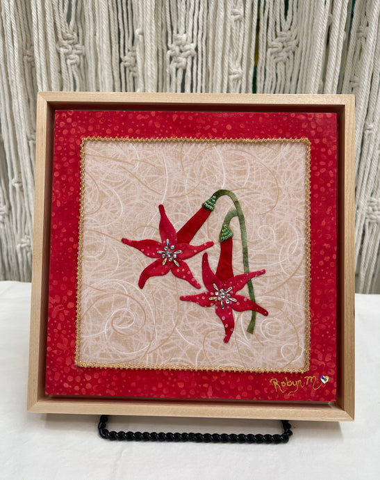 Two red fabric collage flowers with Swarovski crystal centers and green stems on a neutral textile background, mounted on an 8x8 panel