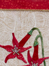 Close-up of red floral fabric applique, Swarovski crystals with green leaves on beige fabric background