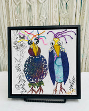 Whimsical textile bird art showing two quirky birds with colorful beaded accents and expressive features on a neutral background