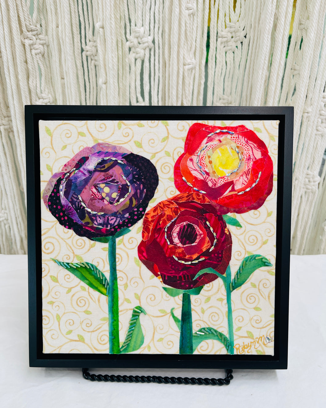 Fabric flower artwork with three layered blooms in red, coral, and purple tones  and Swarovski crystals on 8x8 panel with patterned background