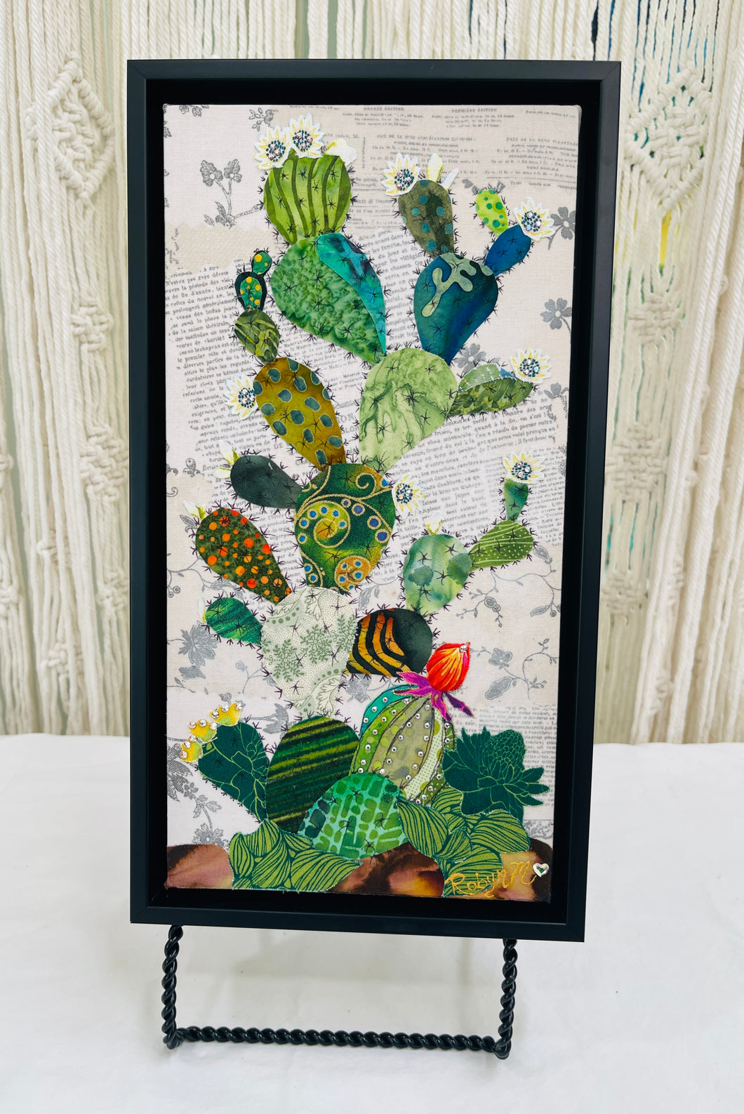 Original cactus fabric artwork 6x12 inches, prickly pear cactus in layered patterned batik fabrics teal gold olive orange with Swarovski crystal white flower centers ink pen spine detail single orange red bloom, vintage toile botanical text background warm brown ground, birch panel, Floral Botanical Collection, Robyn Moore Arts