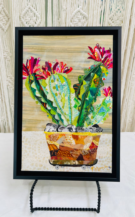 Original potted cactus fabric artwork 8x12 inches, three columnar cacti in patchwork amber rust terracotta fabric pot on fabric wheels with Czech glass bead detail Swarovski crystal blooms in deep magenta crimson pink fabric butterfly detail, wood grain and cream dotted background, birch panel, Floral Botanical Collection, Robyn Moore Arts