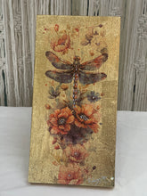 Gold leaf wood panel titled Reverie featuring a dragonfly with outstretched wings over rust-orange poppies, hand-signed by the artist, 6x12 inches.