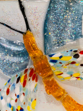 Close-up of a colorful glass butterfly artwork with a yellowish-brown center.