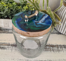 clear glass dog treat canister with wood lid coated in blue green white bronze resin with silver bone