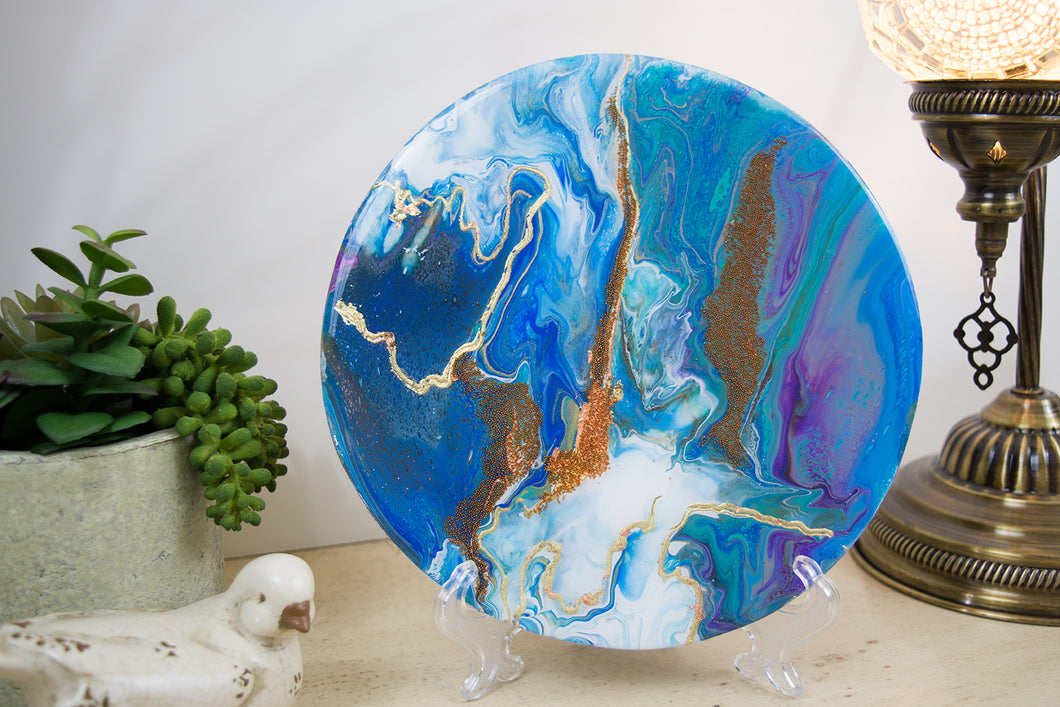 organic swirls of blue, purple, green and white accented with gold foil and copper beads on round wood with resin